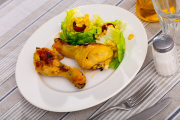 Delicious roasted chicken legs with fresh romaine salad, corn and cherry tomatoes