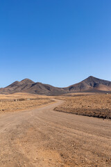 Strange, lunar landscape of the Fuerteventura volcanos and dirt roads in the interior of the island. Mountains, sands