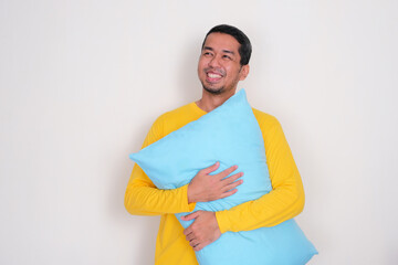 A man look above with happy face while hugging a pillow