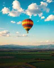 Obraz premium Hot Air Balloon Over Green Fields and Mountains