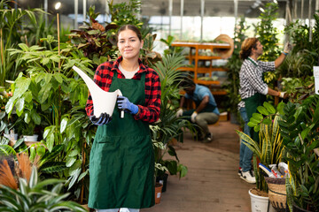 Professional woman florist withe plastic watering can in floral shop
