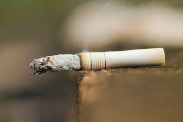 Lit white cigarette with smoke coming out of it sitting on the grey city concrete with copy space	