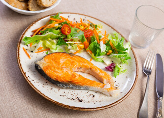 Appetizing baked salmon with fresh salad and vegetables served on platter