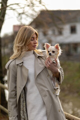 Obraz premium Woman with Chihuahua enjoys a leisurely stroll in a tranquil park setting during autumn