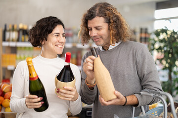 Husband and wife shopping together at the supermarket - choosing bottles of wine