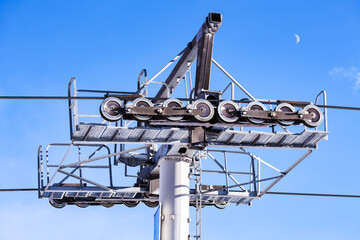 Close-up of a ski lift mechanism with pulleys under a clear blue sky