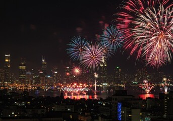 Vibrant fireworks light up night sky over cityscape with skyscrapers reflecting on water