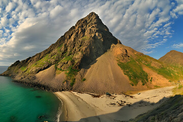Majestic Mountain Peak Overlooks Sandy Beach with Turquoise Waters Under Clouds