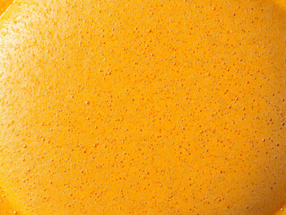 Close-up view of a vibrant orange bubbly surface creates a visually stimulating textured background