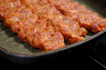 Adana Kebab, the traditional taste of Turkish cuisine. A housewife cooks homemade Adana kebab in a pan. Close-up footage of cooking lavash, kebab in a pan. Traditional Turkish cuisine.
