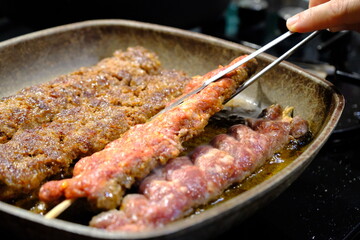 Adana Kebab, the traditional taste of Turkish cuisine. A housewife cooks homemade Adana kebab in a pan. Close-up footage of cooking lavash, kebab in a pan. Traditional Turkish cuisine.