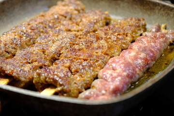Adana Kebab, the traditional taste of Turkish cuisine. A housewife cooks homemade Adana kebab in a pan. Close-up footage of cooking lavash, kebab in a pan. Traditional Turkish cuisine.