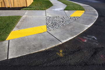 New cement sidewalk around a street corner with accessible disabled ramps, with yellow tactile...