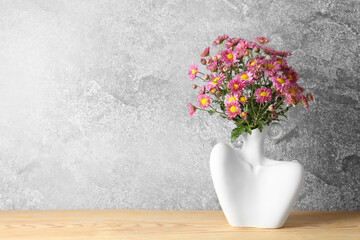 Stylish vase with beautiful flowers on wooden table. Space for text