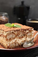 Delicious tiramisu with mint on black wooden board, closeup