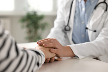 Doctor supporting patient during appointment in hospital, closeup of hands