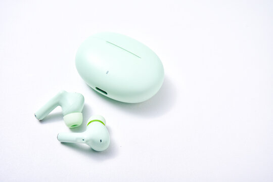 True wireless stereo (TWS) pastel green isolated white background, one type of audio output device that can produce sound without cables
