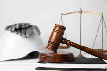 Accident at work concept. Gavel, scales and construction worker's protective gear on white wooden...