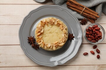 Delicious semolina halva with almond flakes and spices on white wooden table, flat lay