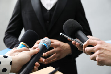 Group of journalists interviewing businessman on grey background, closeup