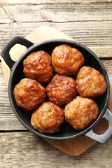 Tasty meatballs in baking dish on wooden table, top view