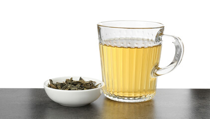 Refreshing green tea in cup and dry leaves on grey textured table against white background. Space for text