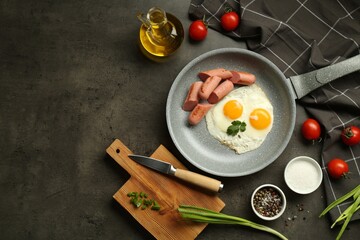 Tasty fried eggs and sausages served on grey table, flat lay. Space for text