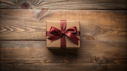 A small gift box with a dark red ribbon bow, presented on a rustic wooden surface