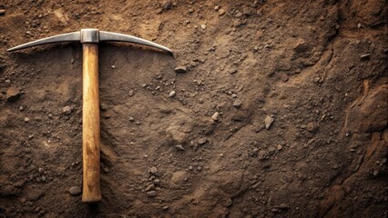 A weathered pickaxe rests on the dark brown soil, ready for excavation