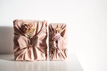 Elegant fabric wrapped gift boxes with dried flowers, styled on white table. Organic and perfect for zero waste holiday.