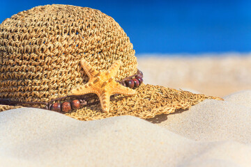 Close-up view of a sun hat on a sandy beach by the sea, selective focus. Beach holiday concept, background with copy space for text