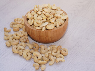 Cashew nuts in wooden bowl on white table with sunshine. Healthy food.