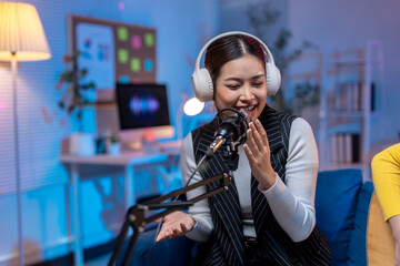 Asian female podcaster broadcasting with her co-host in home studio