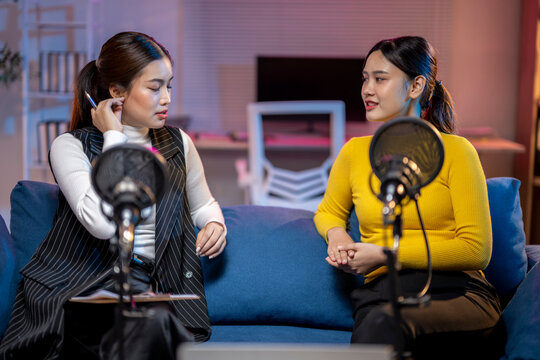 Two asian women discussing during podcast recording session