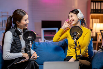 Two asian women having fun recording podcast in home studio