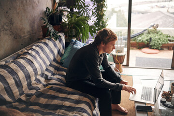Remote work, sofa and man with laptop for typing, proofreading and news story for publication....