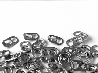 Used aluminum seals from beer can on a white paper background, recyclable material. Rings pull tub opener of soda or beer can, layout frame for vertical poster