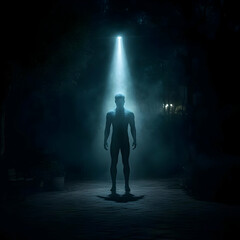 Silhouette of a Man Stands Under a Bright Light in a Dark and Foggy Park at Night, Mysterious and Atmospheric Scene