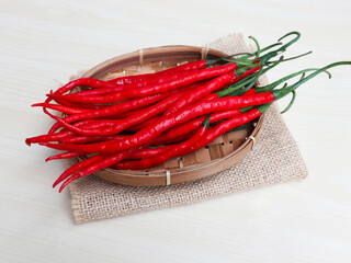 Cabe merah keriting or Curly red chili is most often used in every Indonesian cuisine, giving it a spicy and delicious taste. on a bamboo plate on wooden background