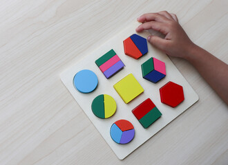 A child plays an educational puzzle toy made of environmentally friendly wood material. geometric...