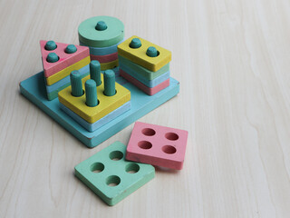 Wooden Stacking Shape Puzzle with pastel color isolated on wooden background