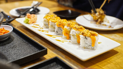 Sushi with cheese topping served on a white plate in a Japanese restaurant