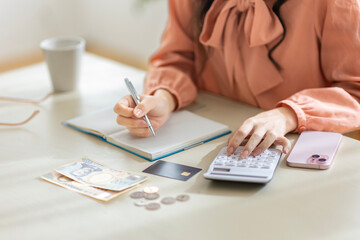 家計簿をつける若い女性の手元