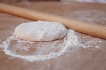 Rolling dough on a wooden surface with flour scattered around