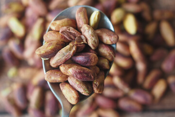 Roasted nuts being held in a spoon on a wooden table