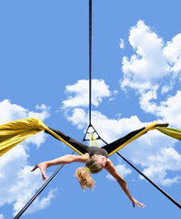 Athletic acrobatic woman spins while opening her arms in a cross hanging upside down with the...