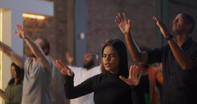 Worship group with diverse individuals raising hands in prayer, eyes closed, emotional expressions, Christian faith community, spirituality, unity in worship, church setting