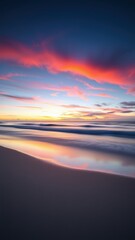 The ocean reflects a vibrant sunrise with pink and orange clouds in the sky