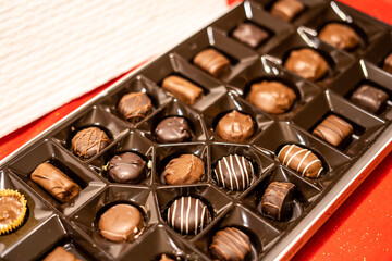 Assorted gourmet chocolates in a box tray, featuring a variety of shapes and designs, ideal for holiday gifting or festive celebrations