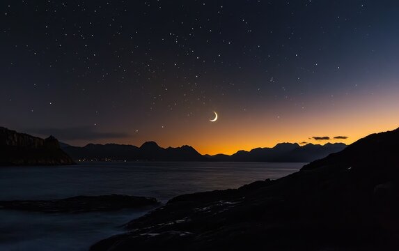 Crescent moon over coastal mountains at night